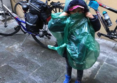 bambina con impermeabile mentre gira Firenze in bici